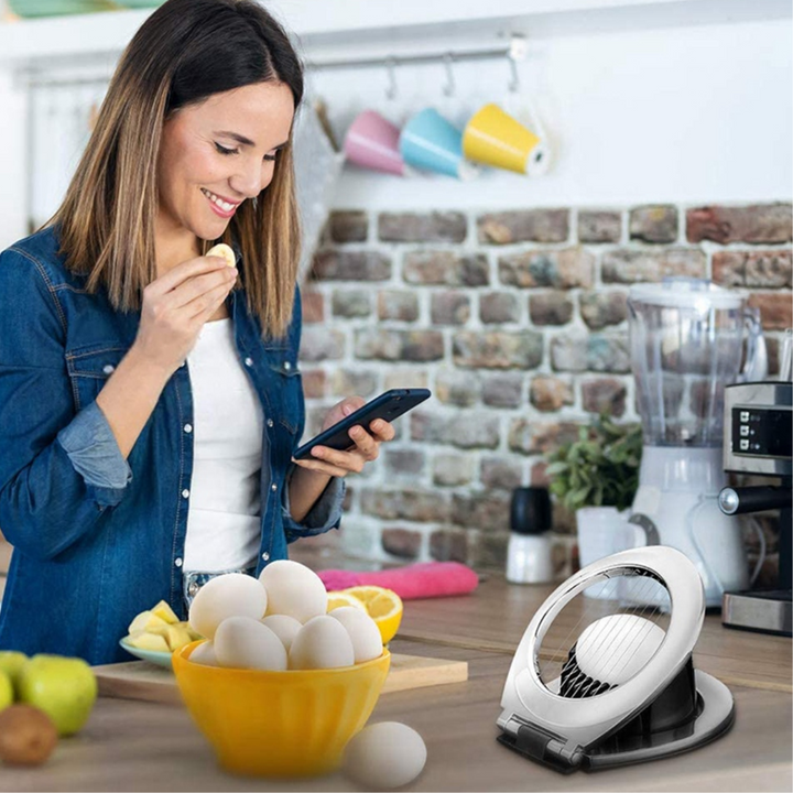 Frau in Küche mit Smartphone, Eierschneider und Schüssel voller Eier, moderne Küchengeräte.