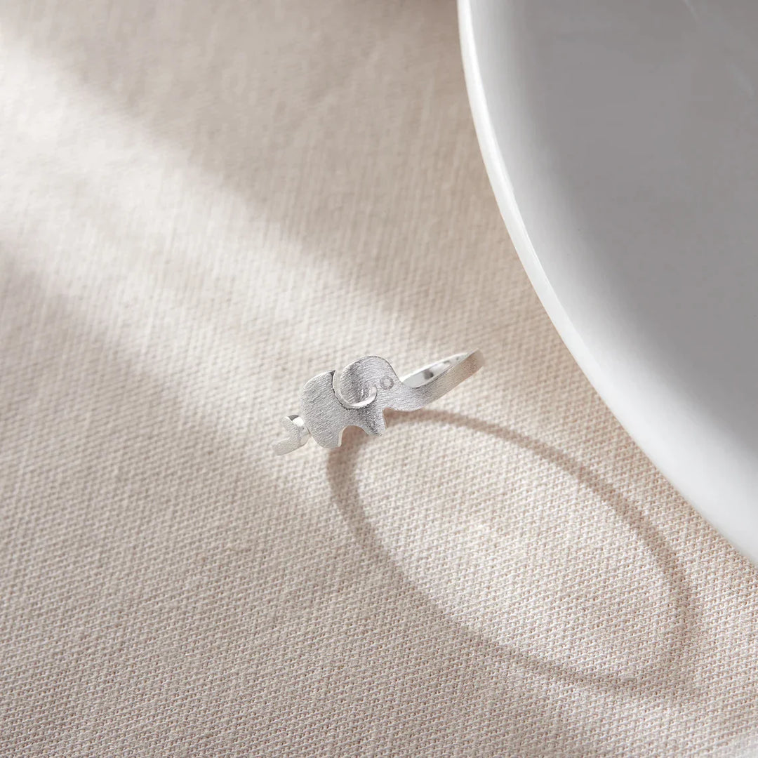 Silberner Elefantenring auf beigem Stoff, eleganter Schmuck, Tiermotiv, Geschenkidee.