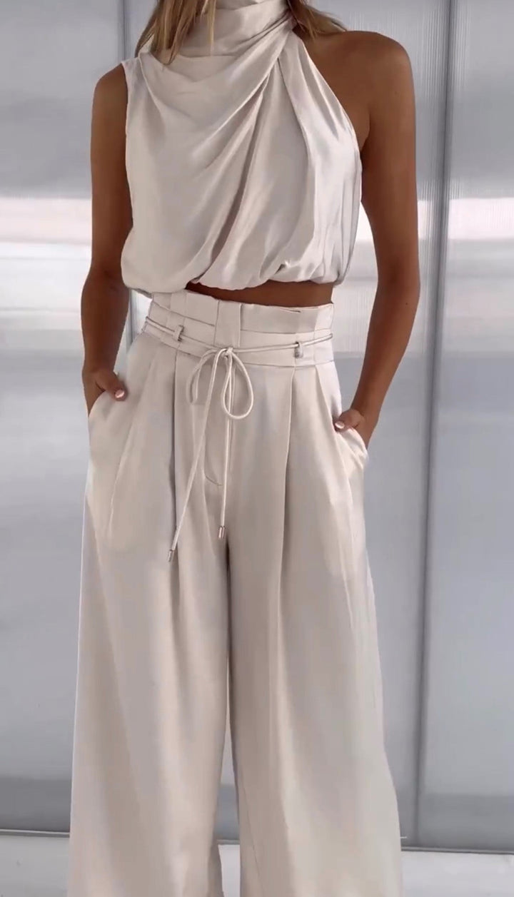 Damen-Outfit aus cremefarbenem Satin, ärmelloses Oberteil und weite Hose, elegant und modern.