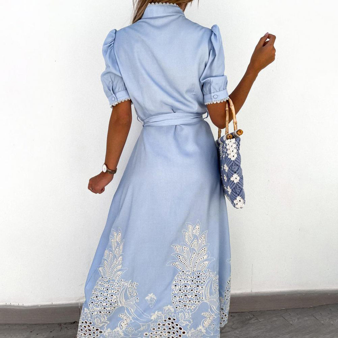 Frau in hellblauem Maxikleid mit Spitze, trägt eine gemusterte Tasche, elegantes Sommeroutfit.
