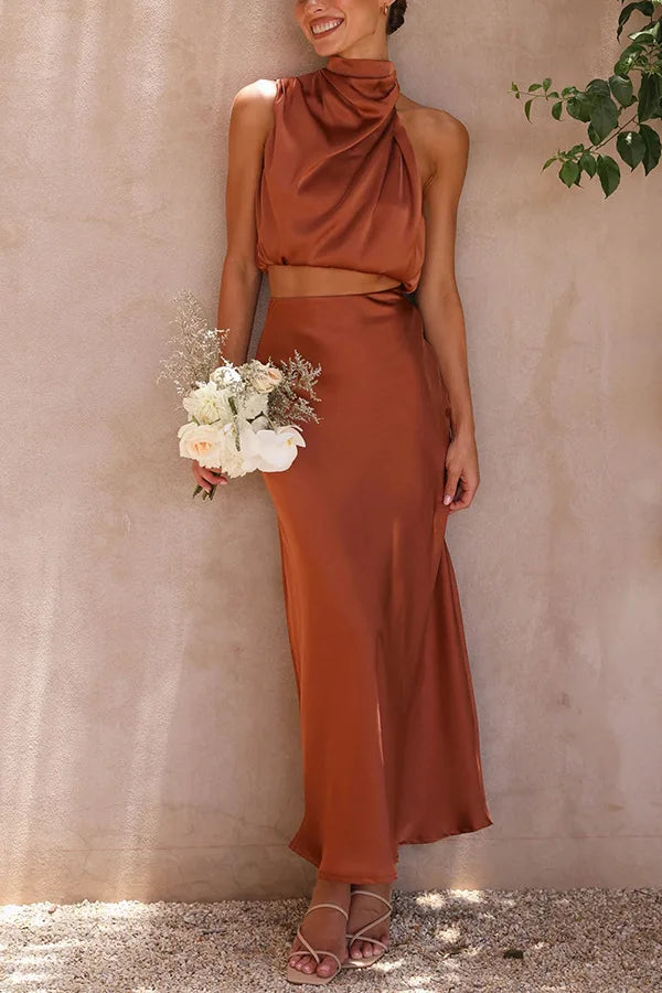 Frau in braunem Satin-Zweiteiler, ärmelloses Top, langer Rock, hält Blumenstrauß.