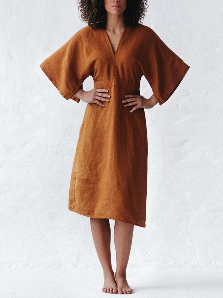 Frau in braunem, lockerem Leinenkleid mit kurzen Ärmeln, elegantes Sommerkleid, Vintage-Stil.