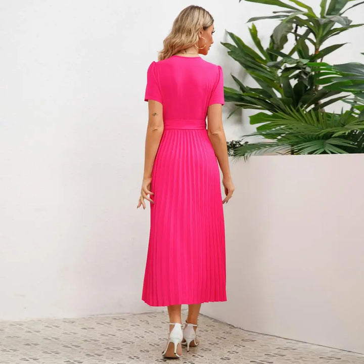 Frau in pinkem Satin-Midikleid mit V-Ausschnitt, Plissee, kurzärmelig, Sommermode 2024.
