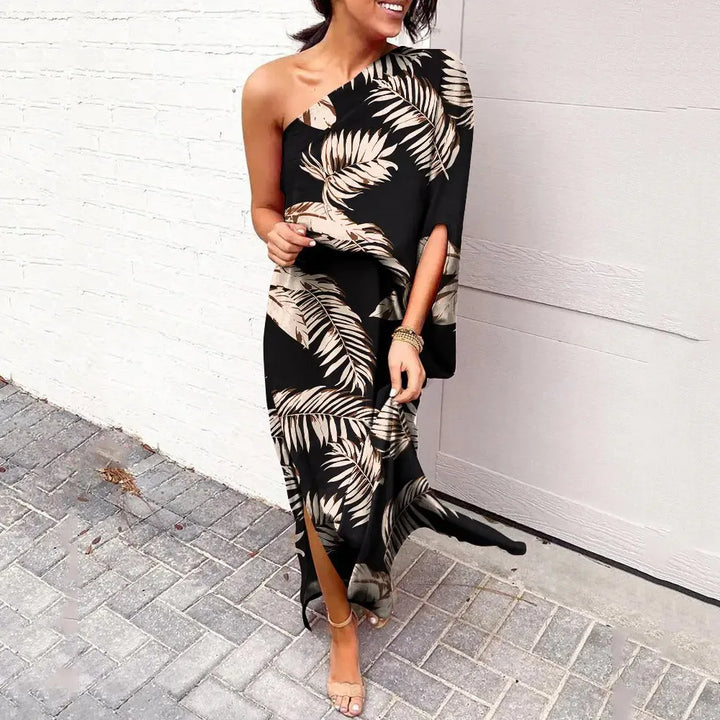 Frau in schwarzem, schulterfreiem Maxikleid mit Palmenmuster, elegant, sommerlich, modisch.