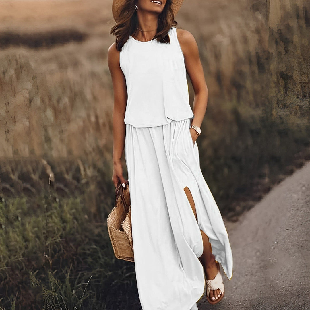 Frau in weißem Sommerkleid mit Strohhut und Korbtasche auf ländlichem Weg.