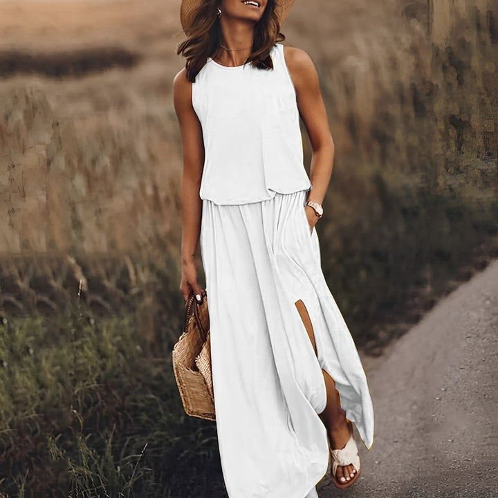 Frau in weißem Sommerkleid mit Strohhut und Korbtasche auf ländlichem Weg.
