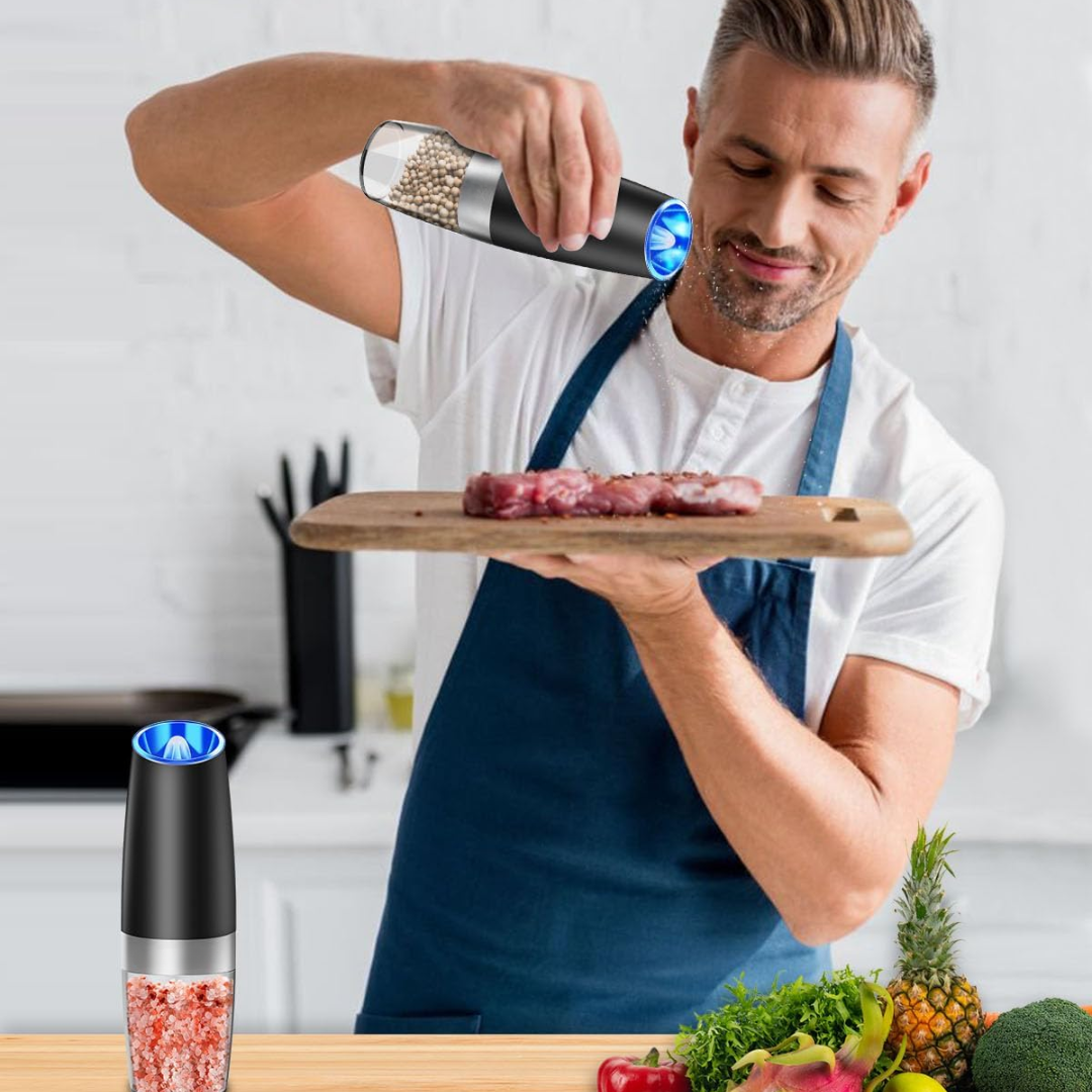 Mann würzt Fleisch mit elektrischem Pfeffermühle, Küche, modernes Design, Edelstahl, LED-Licht.