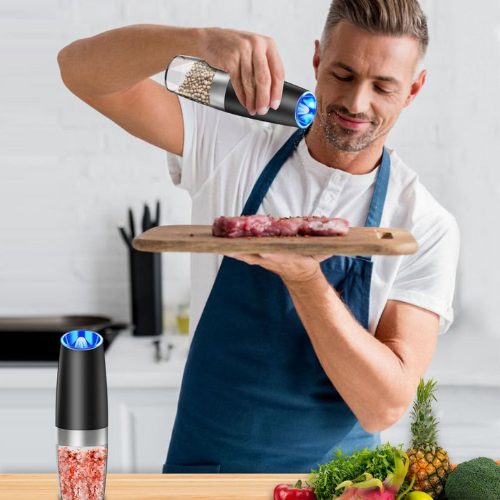 Mann würzt Fleisch mit elektrischem Pfeffermühle, Küche, modernes Design, Edelstahl, LED-Licht.