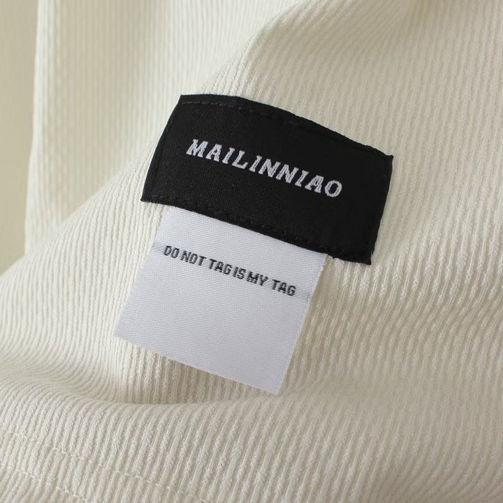 Weiße Stoffstruktur mit schwarzem und weißem Etikett, Text "MAILINNIAO".