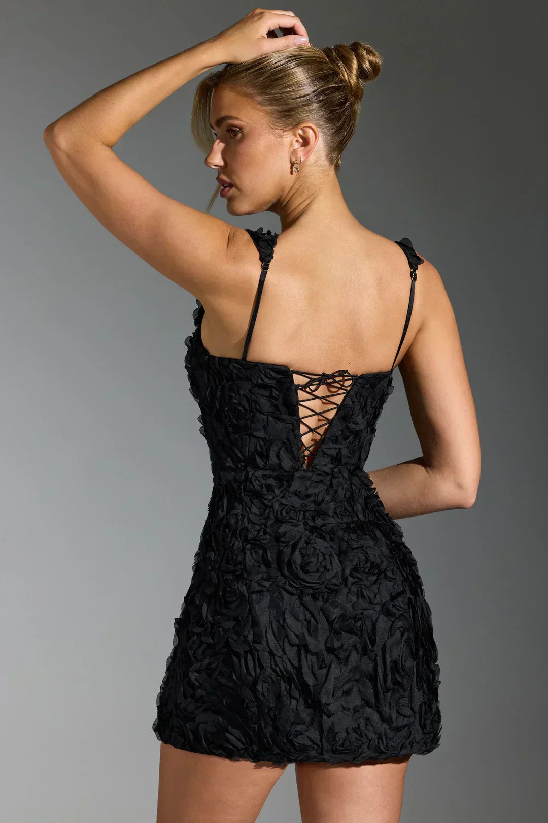 Frau in schwarzem Spitzenkleid mit Rückenschnürung, elegantes Abendmode-Outfit.