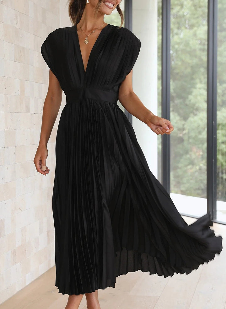 Frau in elegantem, schwarzem, plissiertem Kleid vor Fenster, modisches Abendkleid, Sommermode.