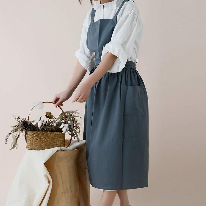 Frau in grauer Schürze arrangiert Blumen in Korb, minimalistischer Stil, Küchenschürze.
