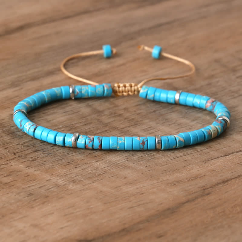 Armband aus türkisfarbenen Perlen, verstellbar, handgefertigt, auf Holztisch.