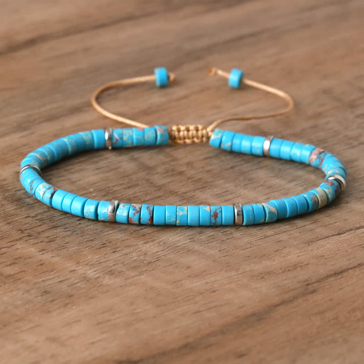 Armband aus türkisfarbenen Perlen, verstellbar, handgefertigt, auf Holztisch.