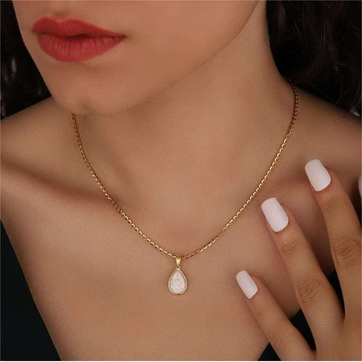 Frau mit goldener Halskette, Tropfenanhänger, weißer Opal, elegante Mode, Nahaufnahme.