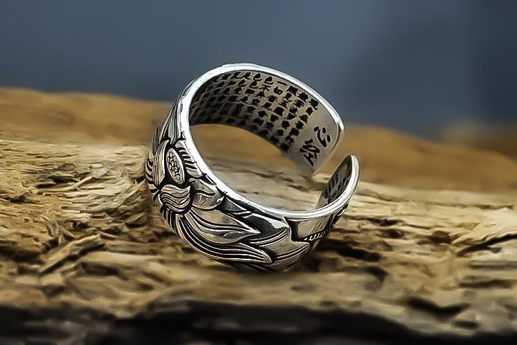 Silberner verstellbarer Ring mit Blumenmuster, handgefertigt, auf Holzuntergrund.