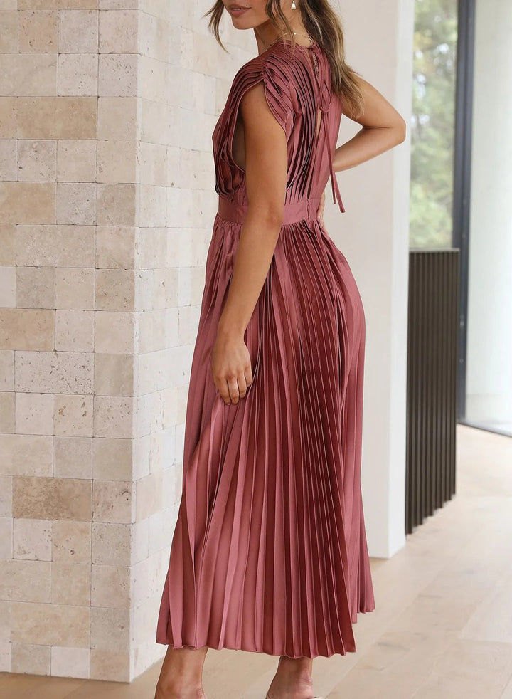 Frau in rosa plissiertem Midikleid, ärmellos, elegantes Design, Innenraum, Modefotografie.