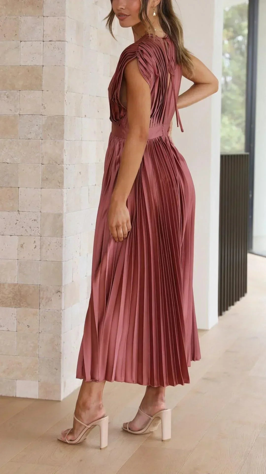 Frau in rosa plissiertem Midikleid, elegantes Design, Sommermode, Innenaufnahme.
