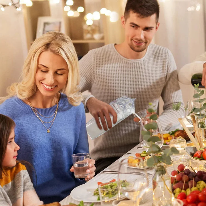 Esstisch mit Familie, Mann gießt Wasser ein, festliche Dekoration, gemütliches Abendessen.