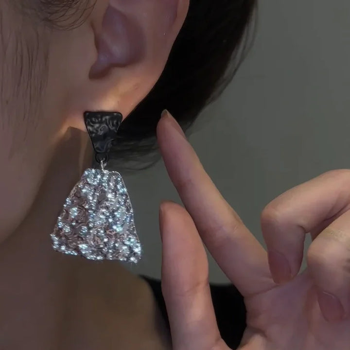 Ohrring mit funkelnden Kristallen, silberfarben, an Ohr getragen, eleganter Schmuck für Damen.