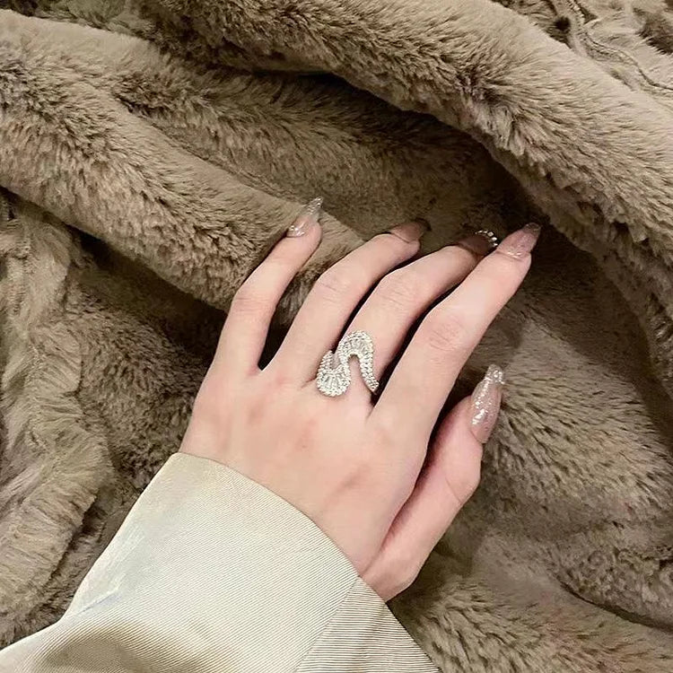 Hand mit silbernem Schwanenring auf beigem Kunstpelz, eleganter Schmuck, Damenmode.