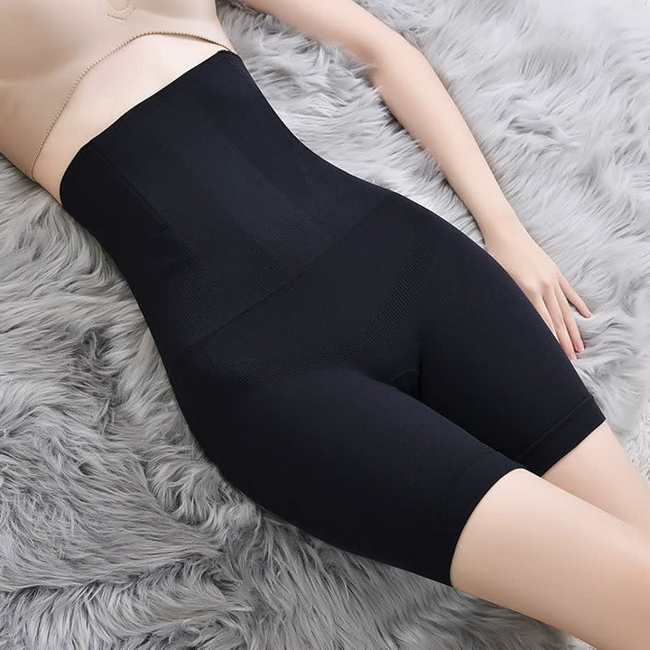 Schwarze nahtlose Shapewear-Shorts, hohe Taille, figurformend, auf grauem Fellteppich.