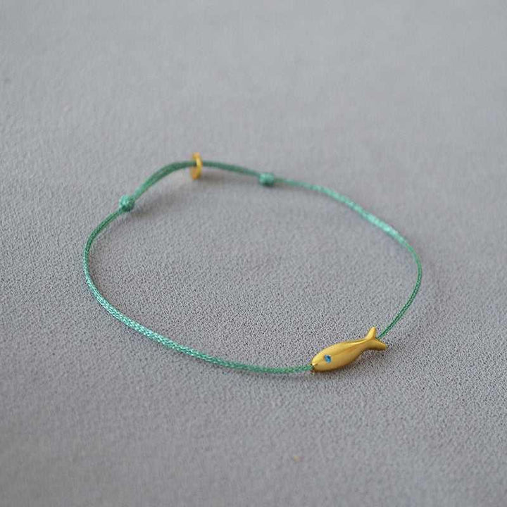 Grünes Armband mit gelbem Fischanhänger, handgefertigt, minimalistisches Schmuckdesign.