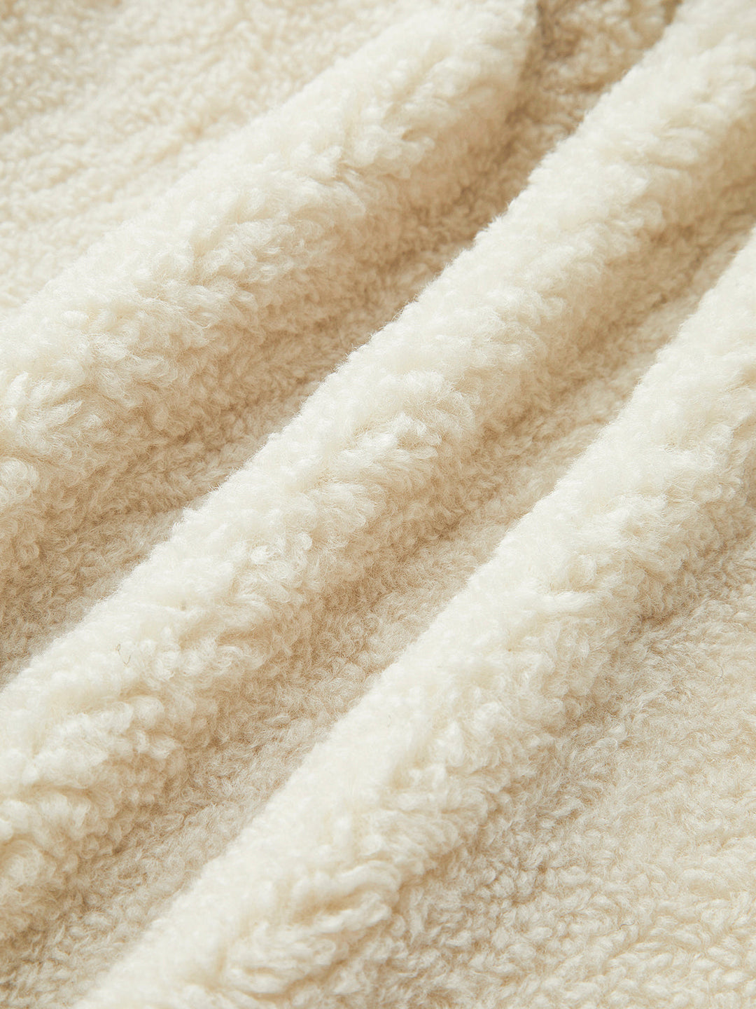 Beige Fleece-Stoff, weiche Textur, ideal für warme Kleidung und Decken, Nahaufnahme.