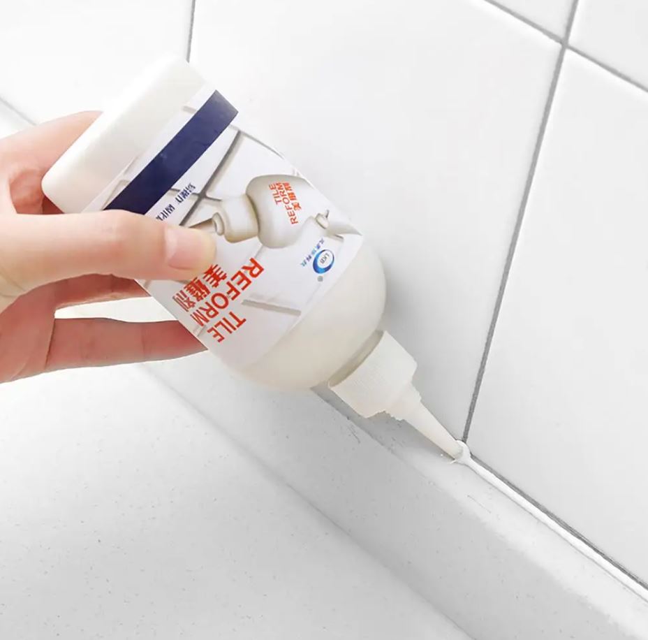 Hand trägt weiße Fugenreparaturpaste auf Fliesenfugen auf, Fliesenreparatur, Heimwerker.