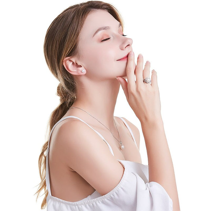 Frau mit Perlenohrringen, Silberkette und Ring, eleganter Schmuck, weißes Kleid, seitliches Profil.