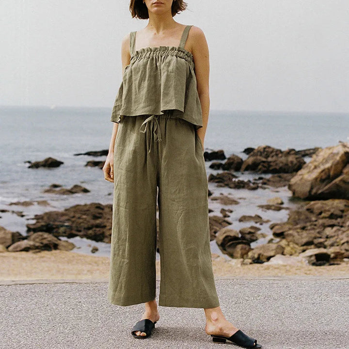 Frau in olivgrünem ärmellosen Rüschen-Top und Hose am Strand, Boho-Sommermode.