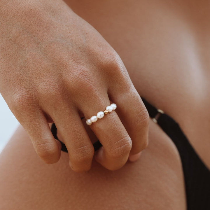Goldener Süßwasserperlenring auf Hand, eleganter Schmuck, Damenmode, Accessoire.