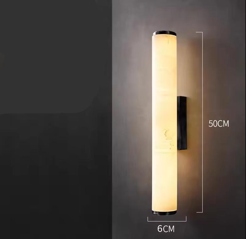 Rozsvícené válcové nástěnné svítidlo na tmavé zdi s kótami udávajícími výšku 50 cm a průměr 6 cm. 21