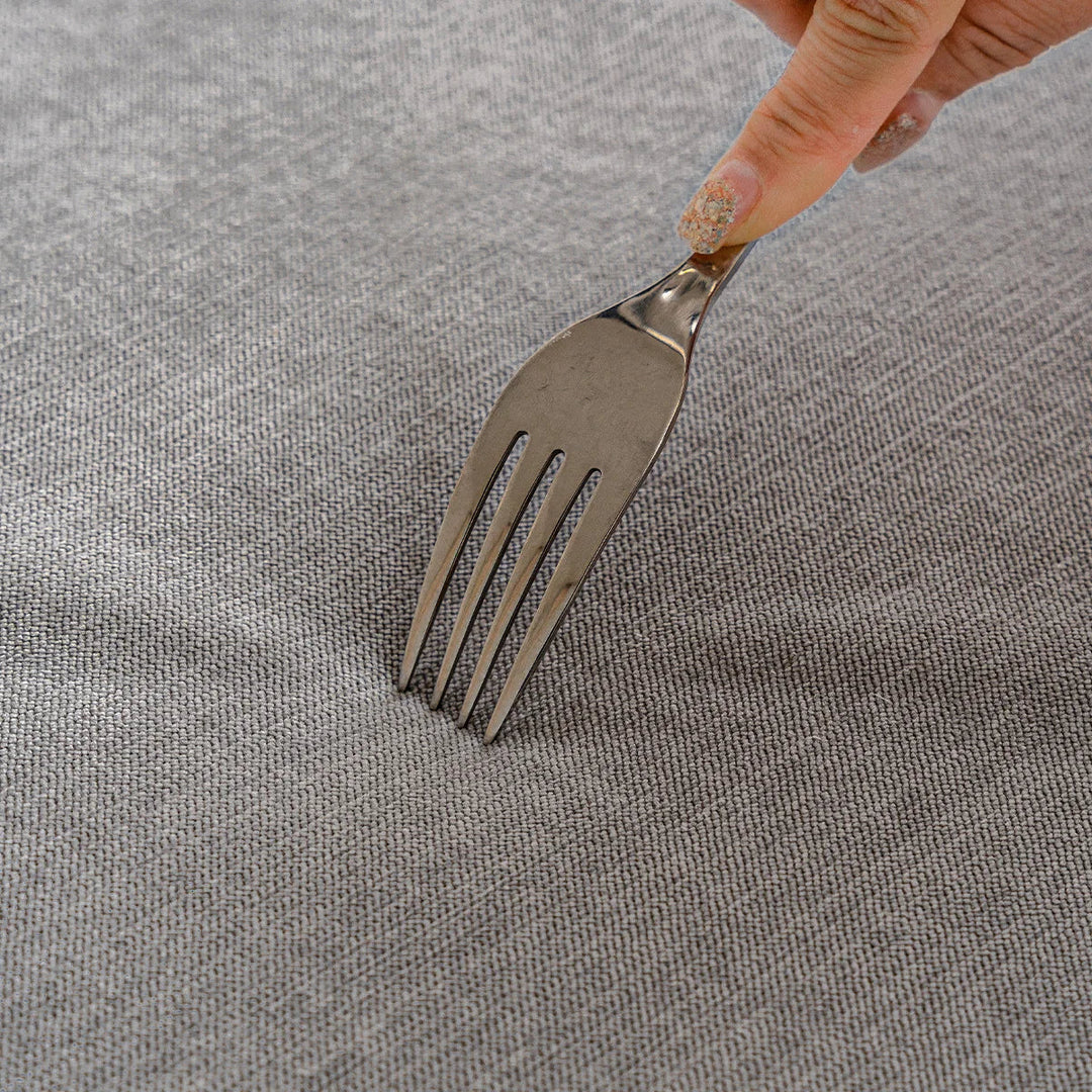 Silberne Gabel auf grauem Stoff, Hand mit glitzerndem Nagellack, Küchengerät, Edelstahl.