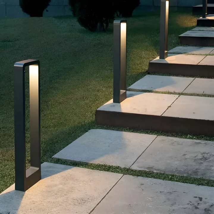 Moderne LED-Wegeleuchten aus Metall beleuchten Gartenweg bei Nacht.