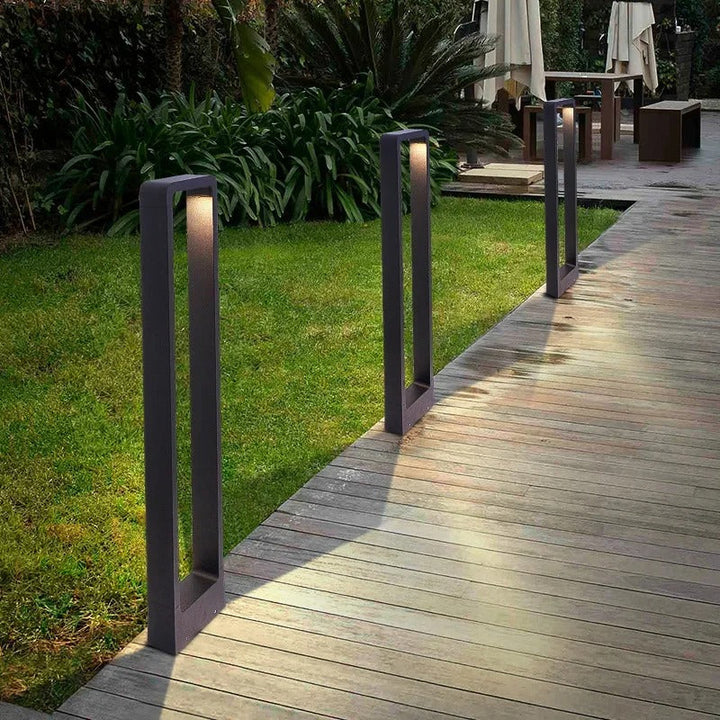 Moderne schwarze Gartenleuchten aus Metall beleuchten Holzweg im Außenbereich.