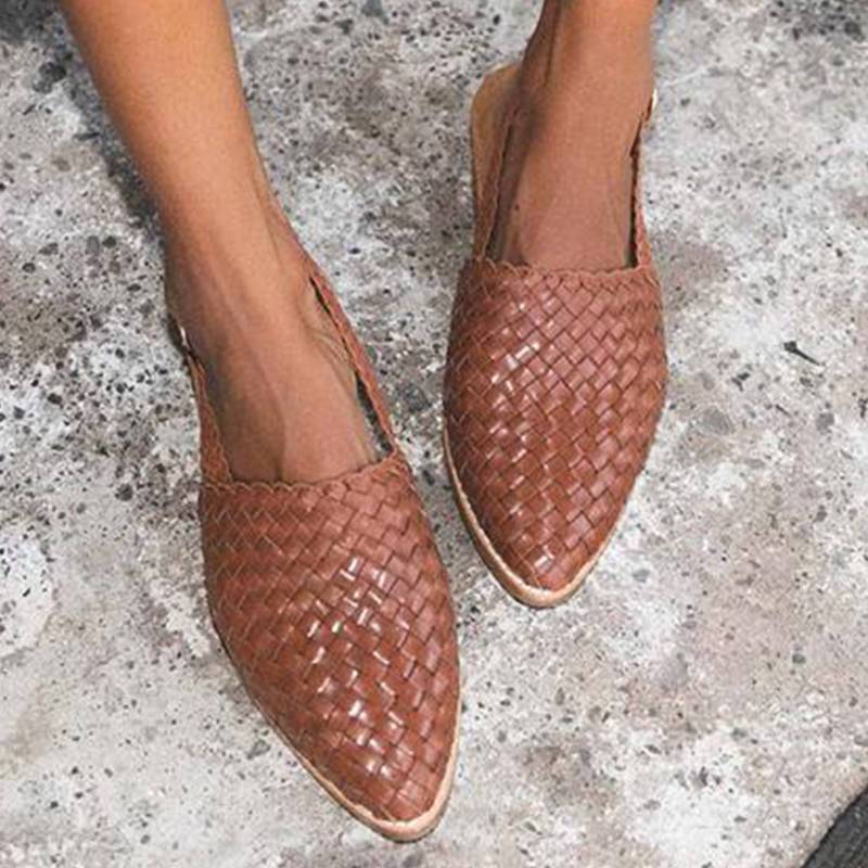 Braune geflochtene Ledersandalen für Damen auf Betonboden.