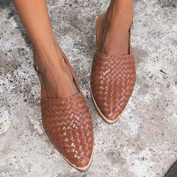 Braune geflochtene Ledersandalen für Damen auf Betonboden.