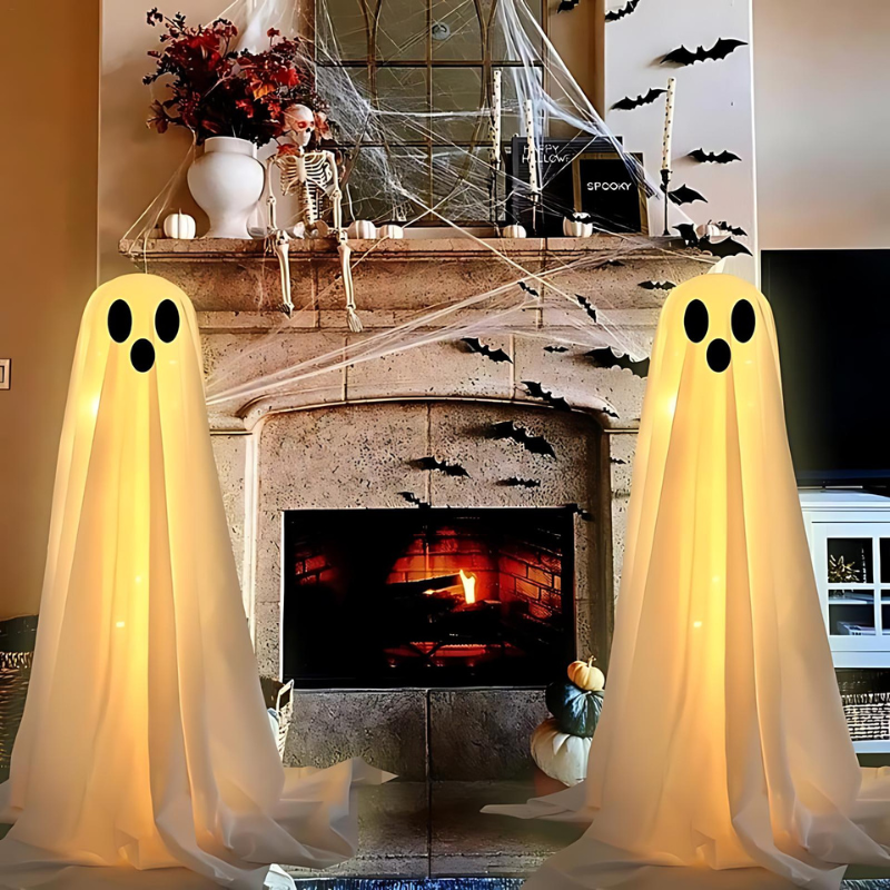 Zwei leuchtende Geisterdekorationen vor Kamin, Halloween-Deko, Spinnweben, Kürbisse.