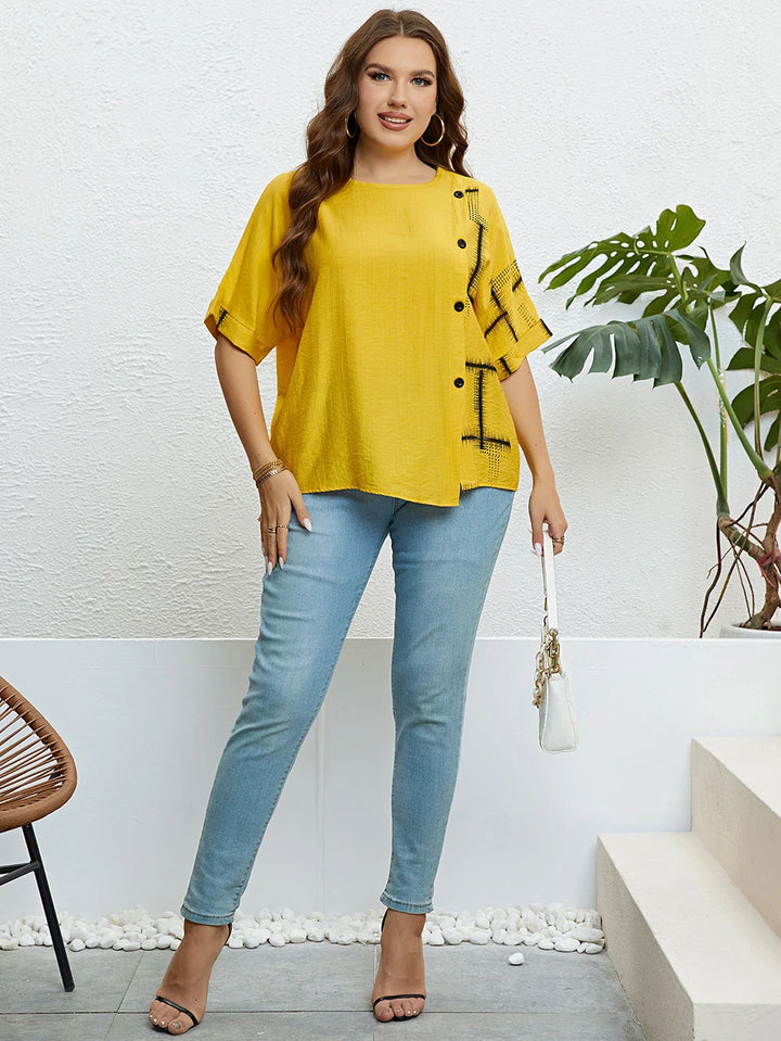 Frau in gelber Bluse und blauer Jeans, steht vor weißer Wand, modisch, lässiger Stil.