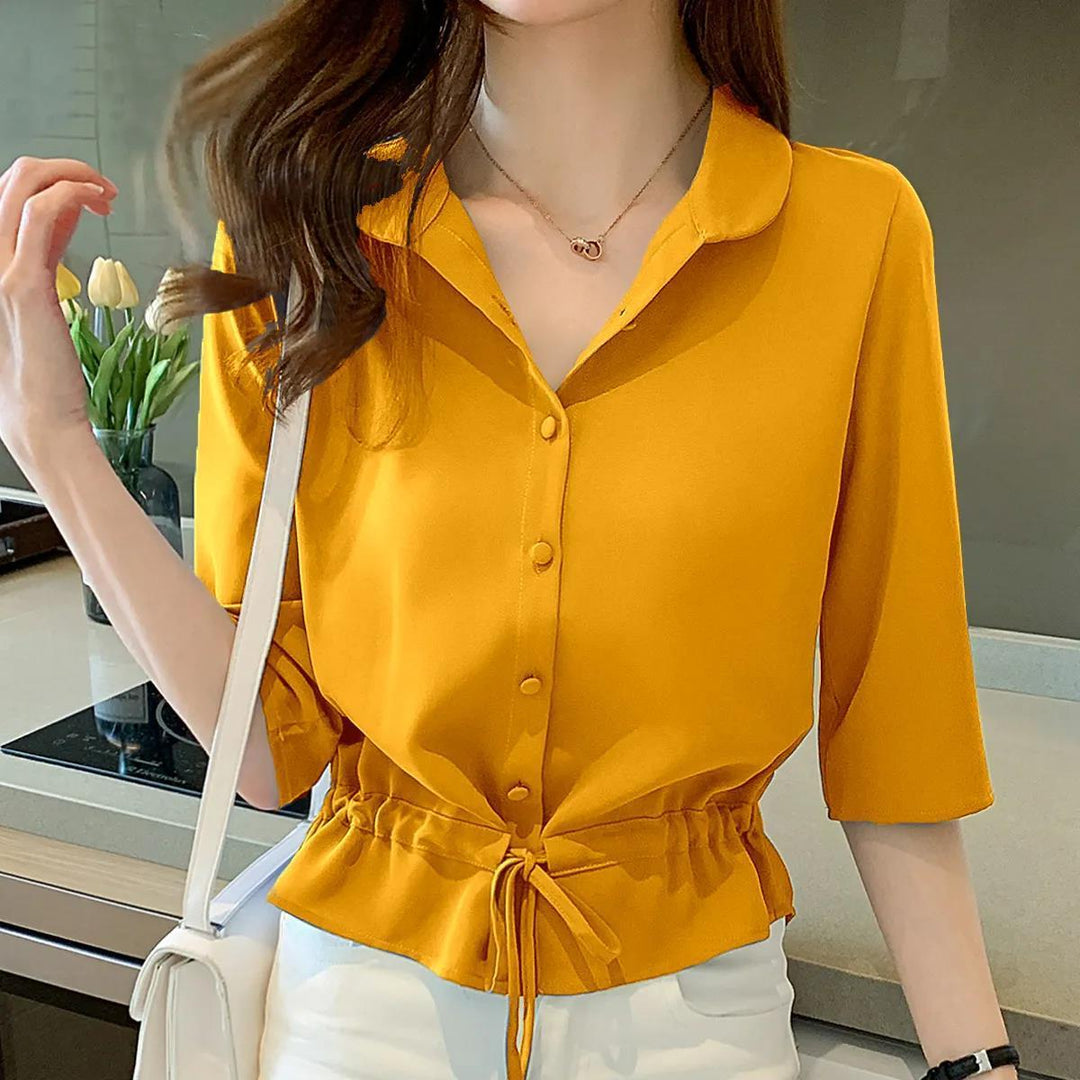 Frau in gelber Bluse mit Knopfleiste und Kordelzug, weiße Hose, moderne Mode.