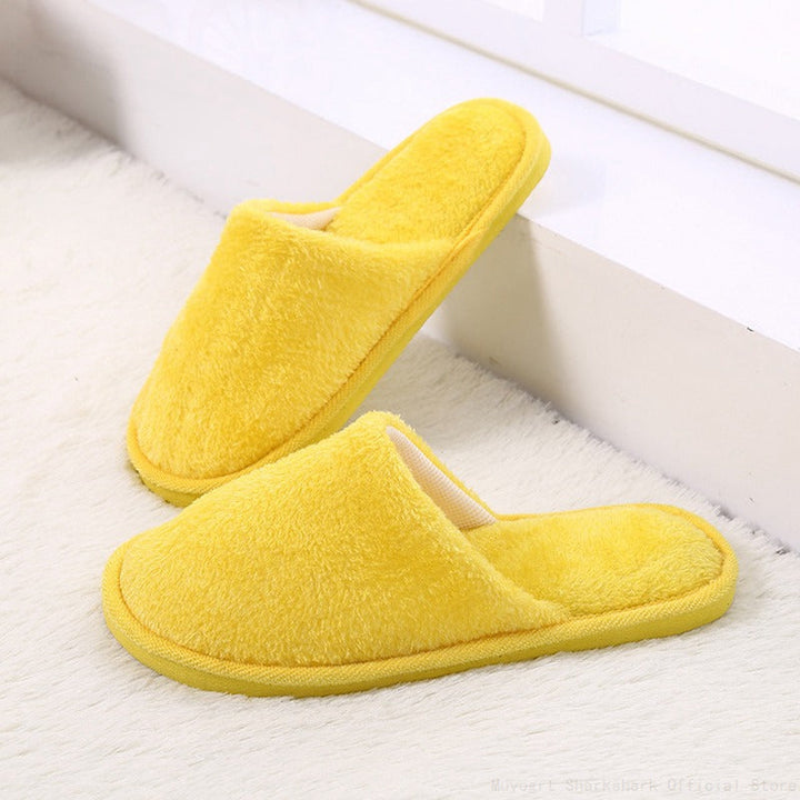 Gelbe Plüschhausschuhe auf weißem Teppich, gemütlich, warm, rutschfest, für Zuhause.