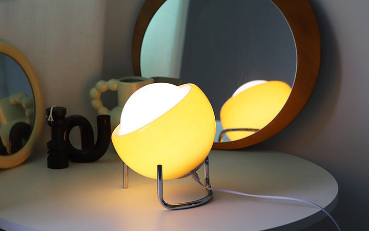 Gelbe Tischlampe auf weißem Tisch vor rundem Spiegel, modernes Design, Innenbeleuchtung.