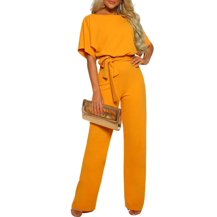 Frau in gelbem Jumpsuit mit Gürtel, hält goldene Clutch, elegante Damenmode.