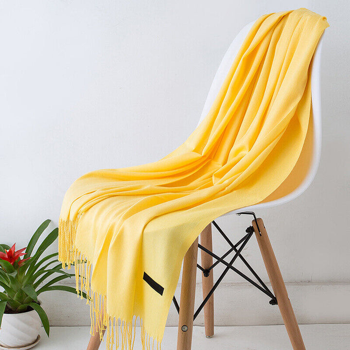 Gelber Kaschmirschal auf weißem Stuhl, weiches Material, modisches Accessoire, Wohnzimmerdeko.
