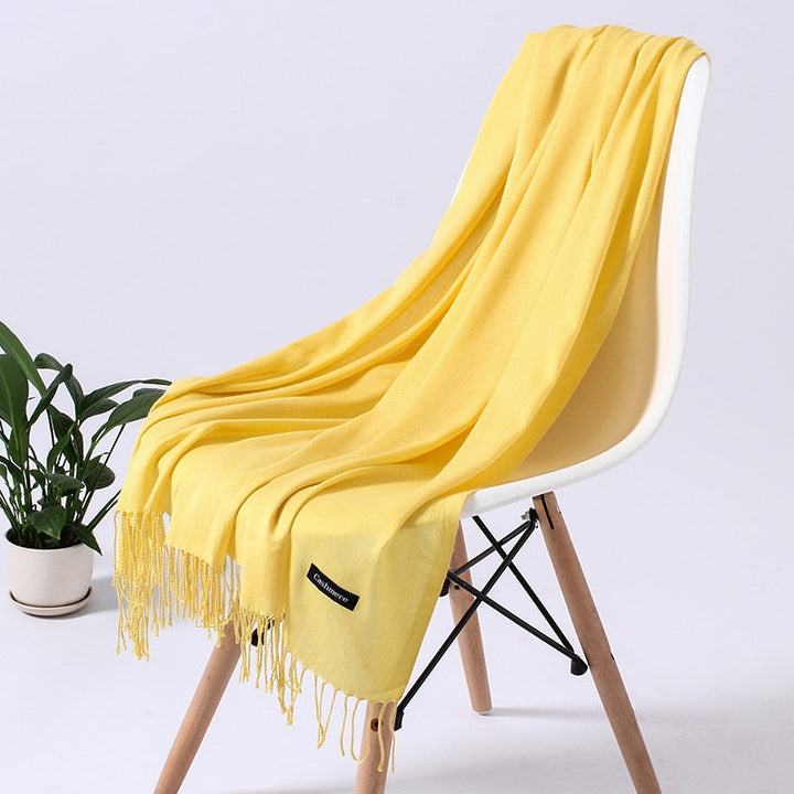 Gelber Kaschmirschal auf weißem Stuhl, weiches Material, modisches Accessoire, Wohnzimmerdeko.