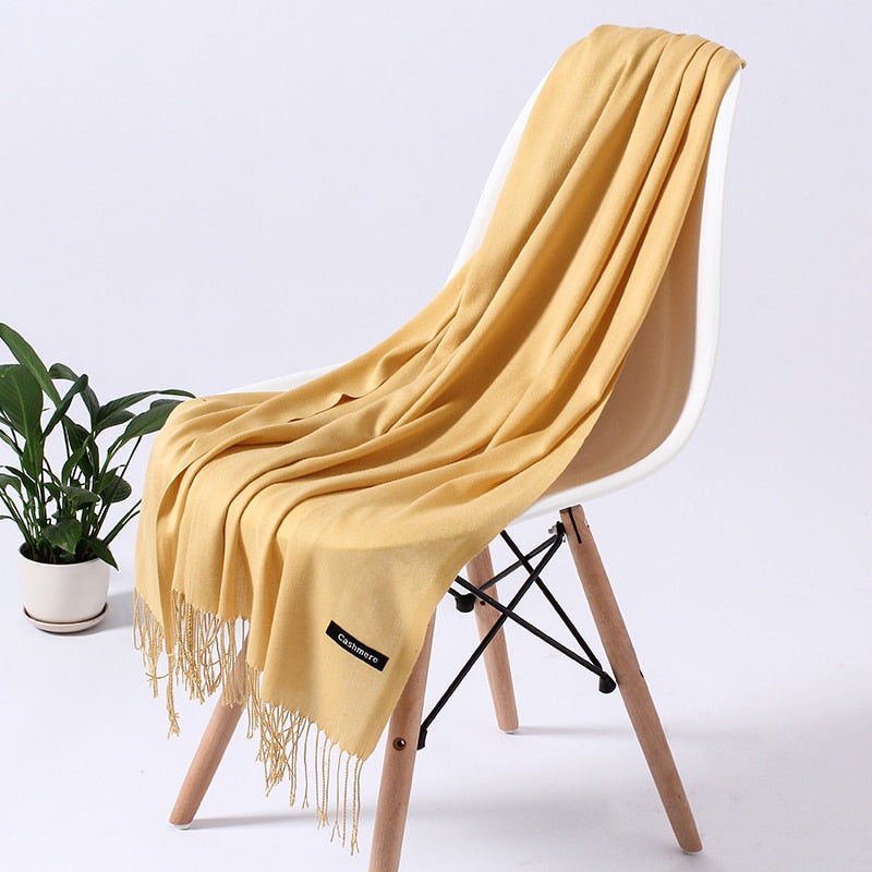 Gelber Kaschmirschal auf weißem Stuhl, weiches Material, modisches Accessoire, Wohnzimmerdeko.