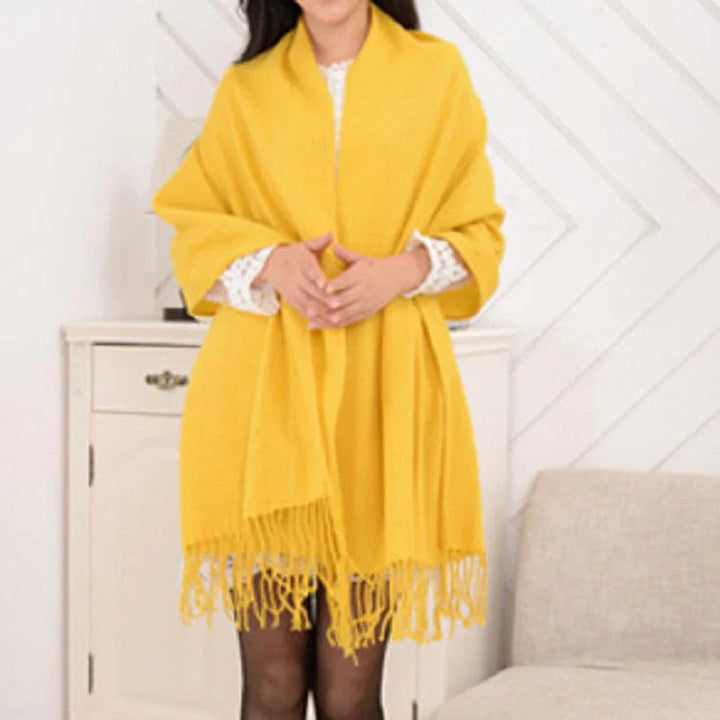Frau mit gelbem Schal, Fransen, weiches Material, modisches Accessoire, Herbst-Winter-Stil.