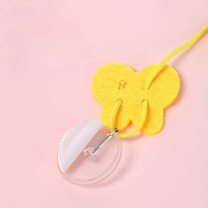 Gelber Schmetterling aus Filz mit Schnur, rosa Hintergrund, DIY-Dekoration, Bastelmaterial.