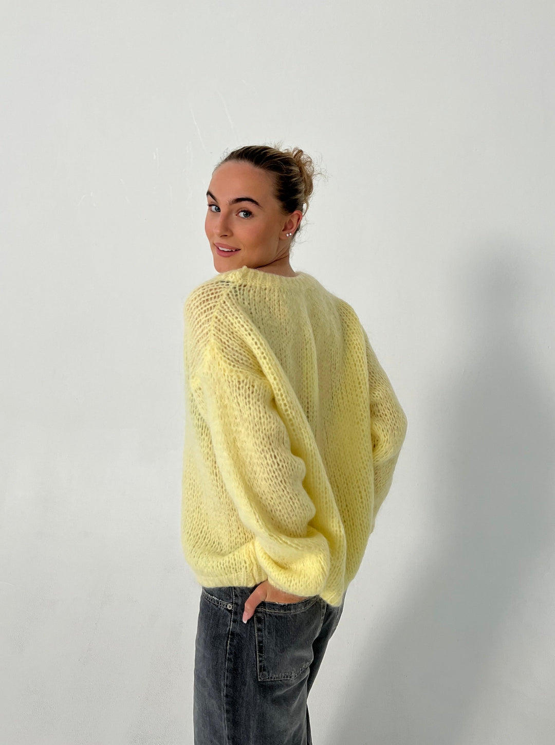Frau in gelbem Strickpullover, lässig, modisch, Herbstmode, Damenbekleidung, Rückansicht.